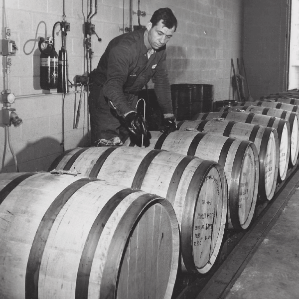 A team member at A. Smith Bowman Distillery preparing white oak barrels, circa 1950.